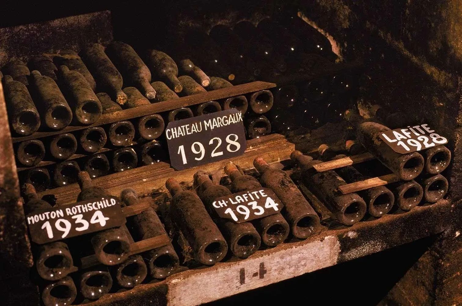 Old dusty wine bottles labeled with years in a cellar.