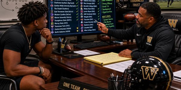 Coach and player discuss strategy in a football office.