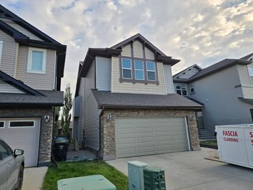 Suburban two-story house with a double garage and cloudy sky.