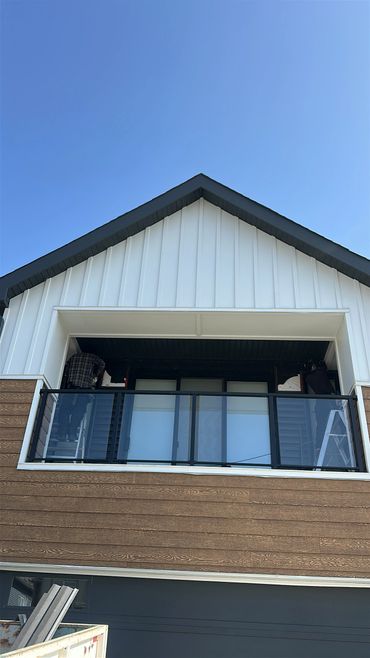Two workers on ladders fixing or installing something on a balcony ceiling.