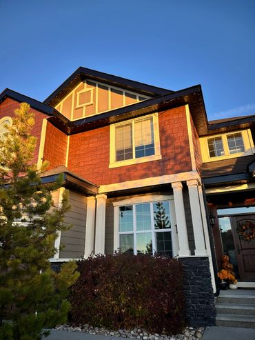 Sunlit house exterior with autumn decorations and clear blue sky.
