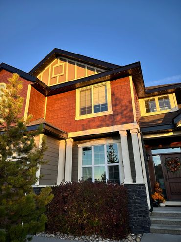 Sunlit suburban house with autumn decorations and clear blue sky.