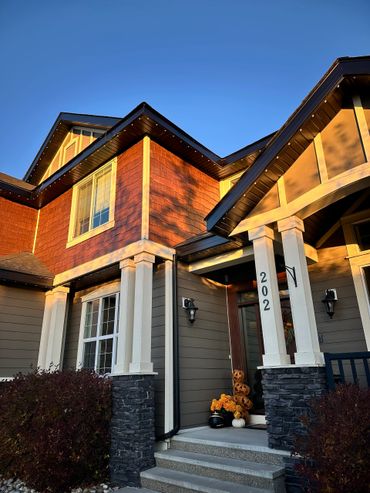 House entrance decorated with Halloween pumpkins and flowers at sunset.