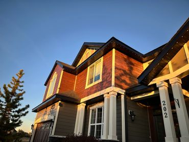 Modern two-story house illuminated by warm sunset light under a clear blue sky.