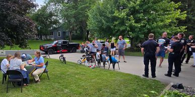 Community gathering with people and police officers in a suburban neighborhood.