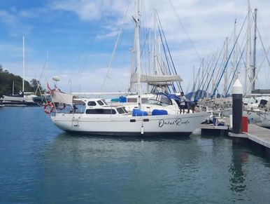 Ombak Rindu yacht moored at a marina, surrounded by other sailboats under a clear blue sky