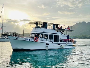 Sea-E-O boat on calm waters at sunset, with guests on the upper deck and mountains in the background