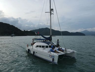 Lorelai catamaran cruising on calm waters with guests relaxing on deck, surrounded by scenic islands