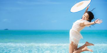 Happy girl jumping on a tropical beach with clear blue waters