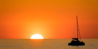 Silhouette of a sailing yacht at sea during a vibrant orange sunset