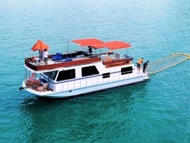 Langkapuri yacht with red canopies, floating on turquoise waters with a sea net behind