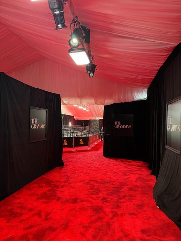 Red carpet area for The Grammys with black curtains and overhead lighting.