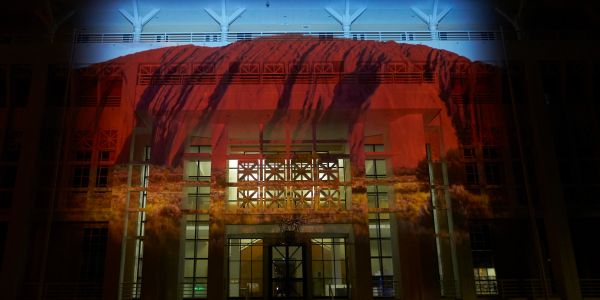 A building facade illuminated with a red and orange projection resembling flames.