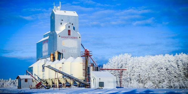 A grain elevator in snowy Saskatchewan under a clear blue sky.