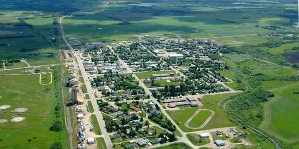 Aerial view of a small town surrounded by green fields and open land.