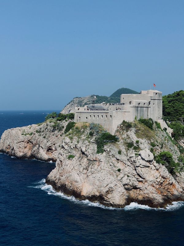 A historic fortress perched on a rocky coastline overlooking the sea.