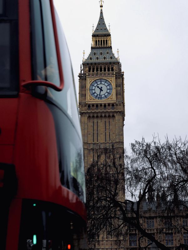 Big Ben clock tower with a red double-decker bus in London.