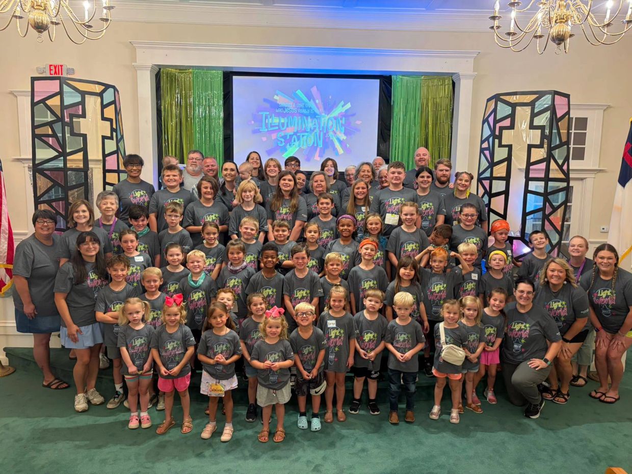 Large group of children and adults in matching shirts inside a church.