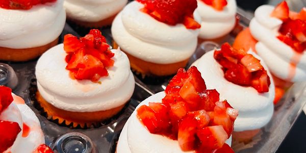 Cupcakes topped with fresh diced strawberries and creamy white frosting.