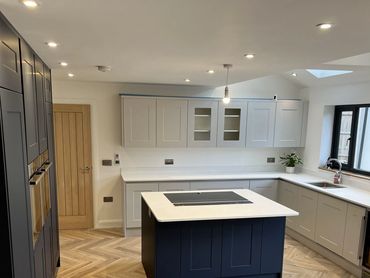 Modern kitchen with navy and white cabinets, island, and herringbone floor.