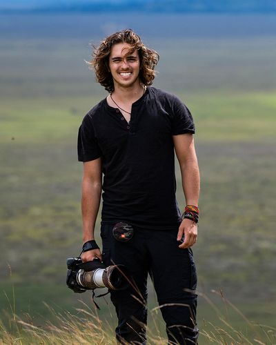 Young man with a camera in a natural outdoor setting.