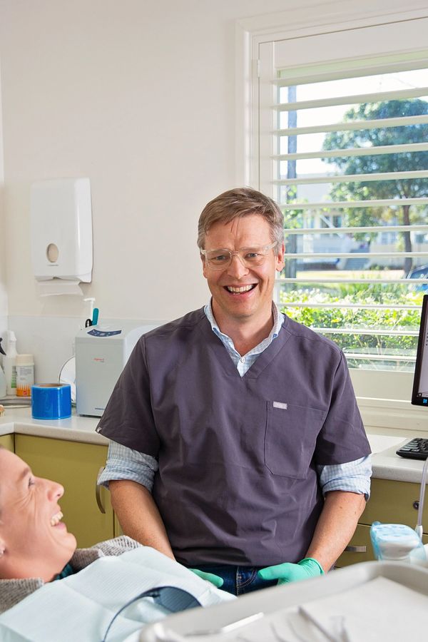 A beautiful photo of Dr Jonathan Loughlin in surgery, laughing with one of his patients. 