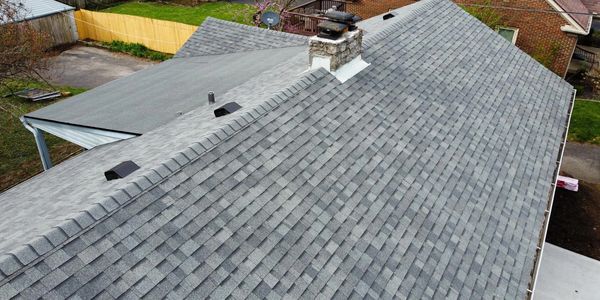 New grey shingle roof with chimney.