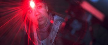 Woman illuminated by a bright red light on her forehead.