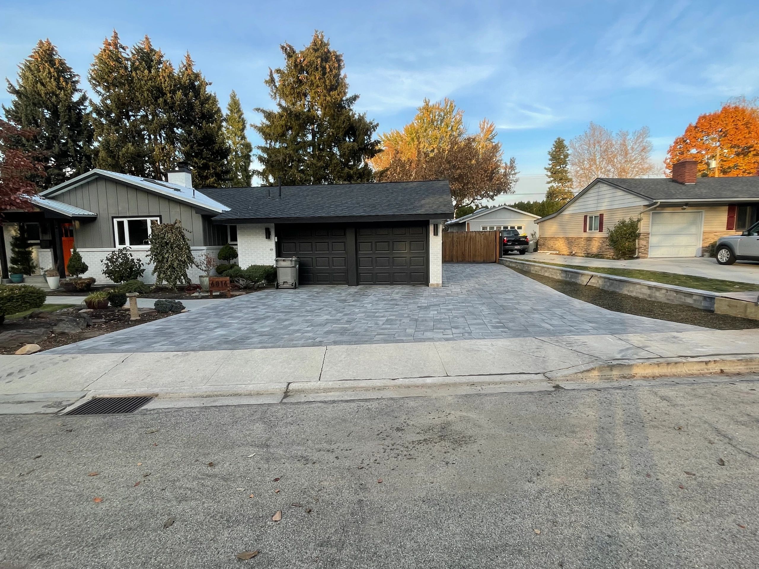 Residential houses with large driveways and trees.