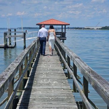 Couple walking on wooden pier by water