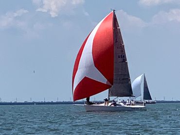 A sailboat with a billowing red sail in Lake Pontchartrain near North Shore Beach.