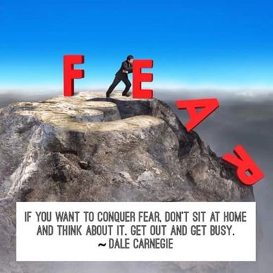 Man pushing letter E to complete the word FEAR on a mountain cliff.