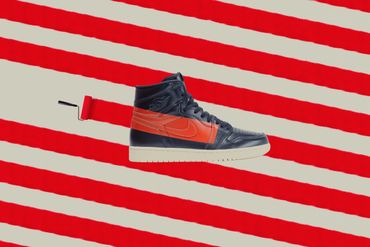 A shoe getting a stripe painted on it in front of a patterned background of the same painted stripe