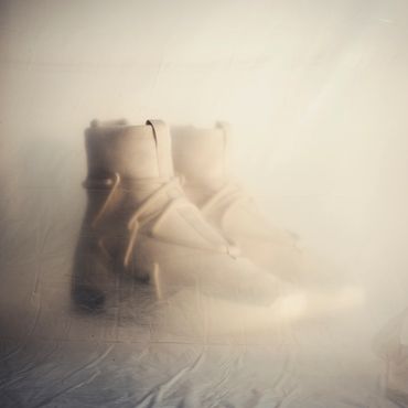 High top sneaker boots behind a plastic tarp in a dusty mysterious location