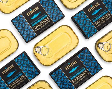 An organized group sardine tins; some with the packaging still on, some without.