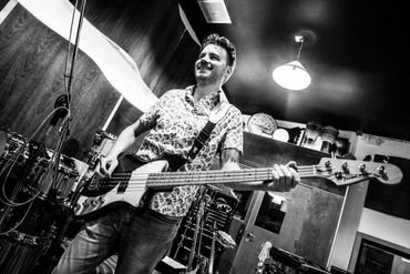 Nick smiling while in playing his bass guitar.