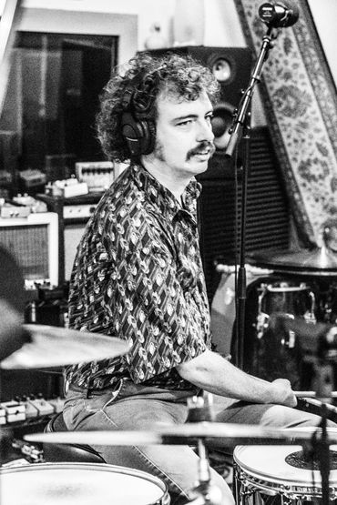 Derek looking attentive while sitting at the drums in the studio.