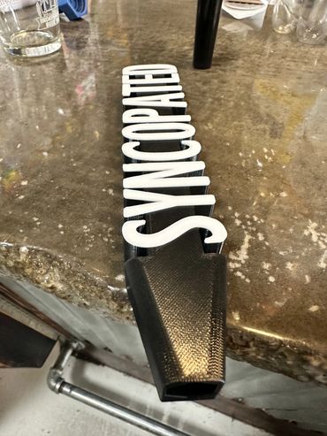 A Syncopated tap handle resting on the bar