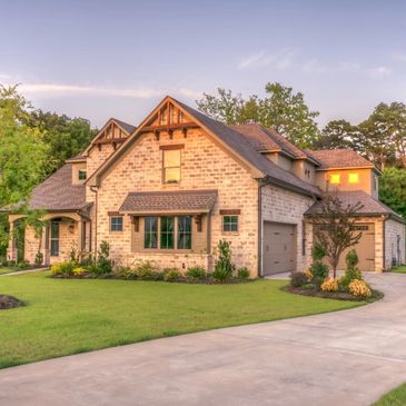 Home Insurance. House with a green garden and big driveway.
