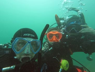 Three scuba divers underwater wearing masks and breathing apparatus.