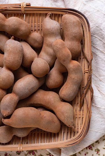 Tamarindo en una canasta de madera sobre una mesa con un mantel de tela