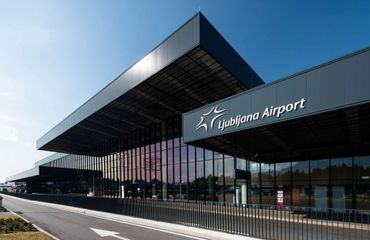 Modern exterior of Ljubljana Airport terminal under clear sky.