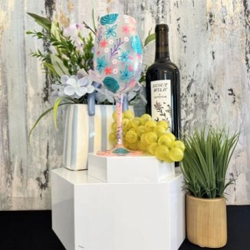 Decorative wine bottle setup with grapes and flowers.