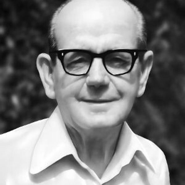 Portrait of an elderly man wearing glasses and a white shirt.