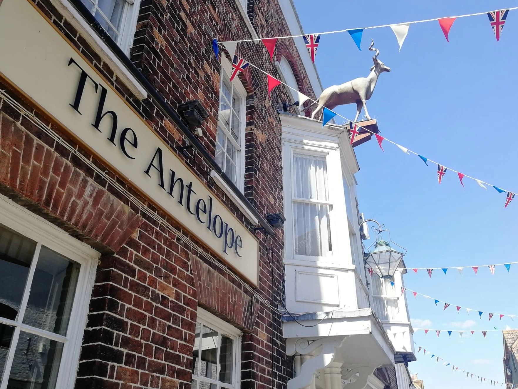The Antelope Pub with a clear sign on red brick building and sculpture of an antelope above a window