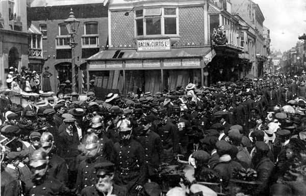 Parade by 'Bacon & Curtis LTD', people dressed in suits and flap caps or military dress,