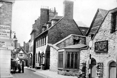 An old photo of Scaplen's Court, a stone building with period houses in the background