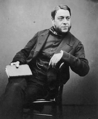 Photo portrait of a bearded man leaning in a chair with a book, dressed in a smart period suit