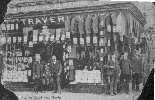 Clothing piled up outside store and coats/suits hanging up; men and boys outside