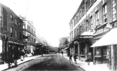 Old photo of the HighStreet with the London Hotel on the right & blurred people walking outside it